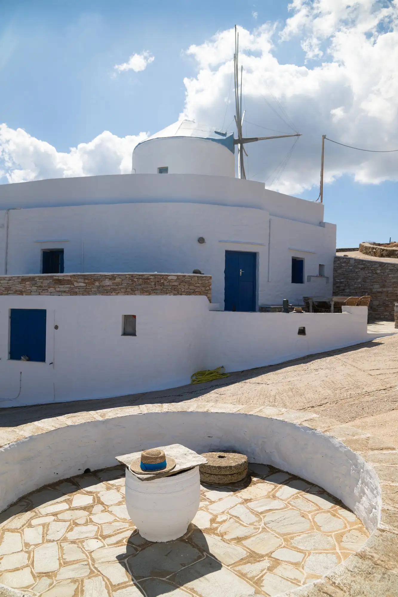 Bâtiments blancs aux portes bleues, avec le moulin derrière eux