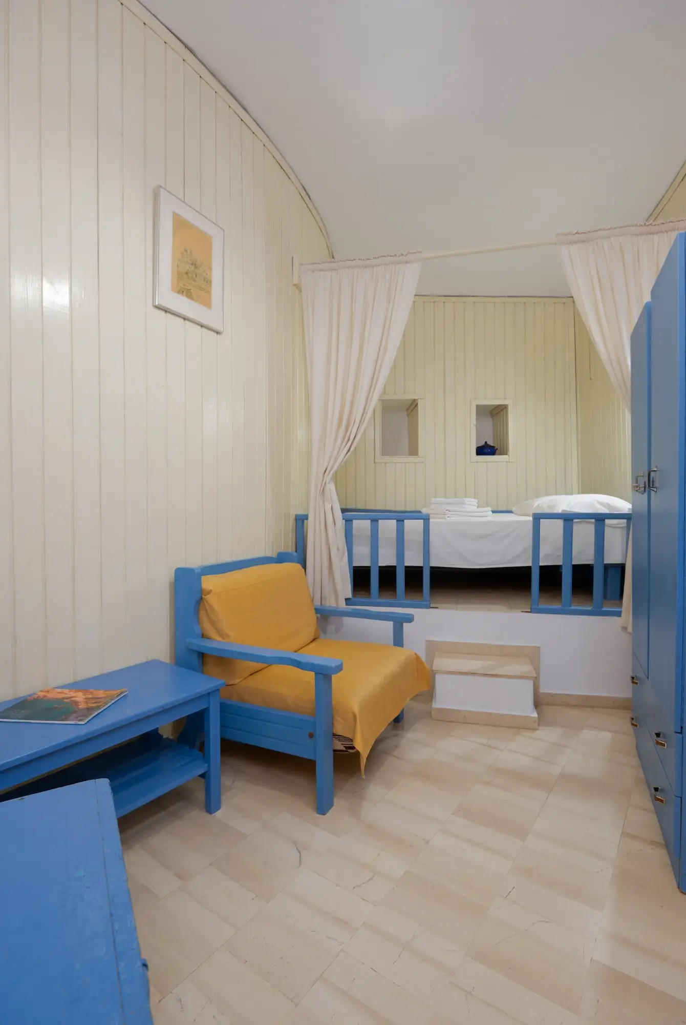 Appartement Eos : coin salon avec fauteuil et chambre surélevée