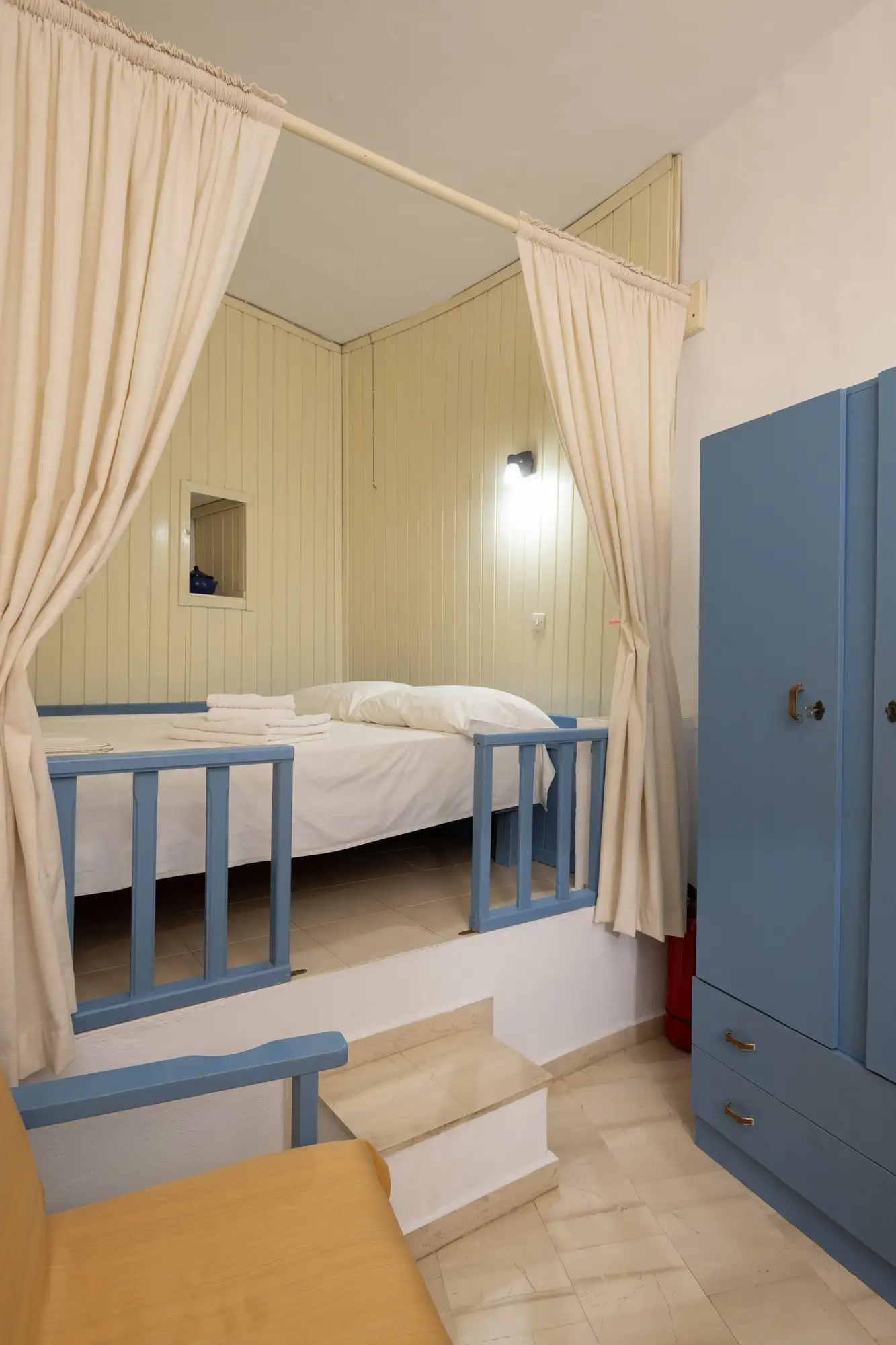Appartement Eos : chambre surélevée derrière des rideaux