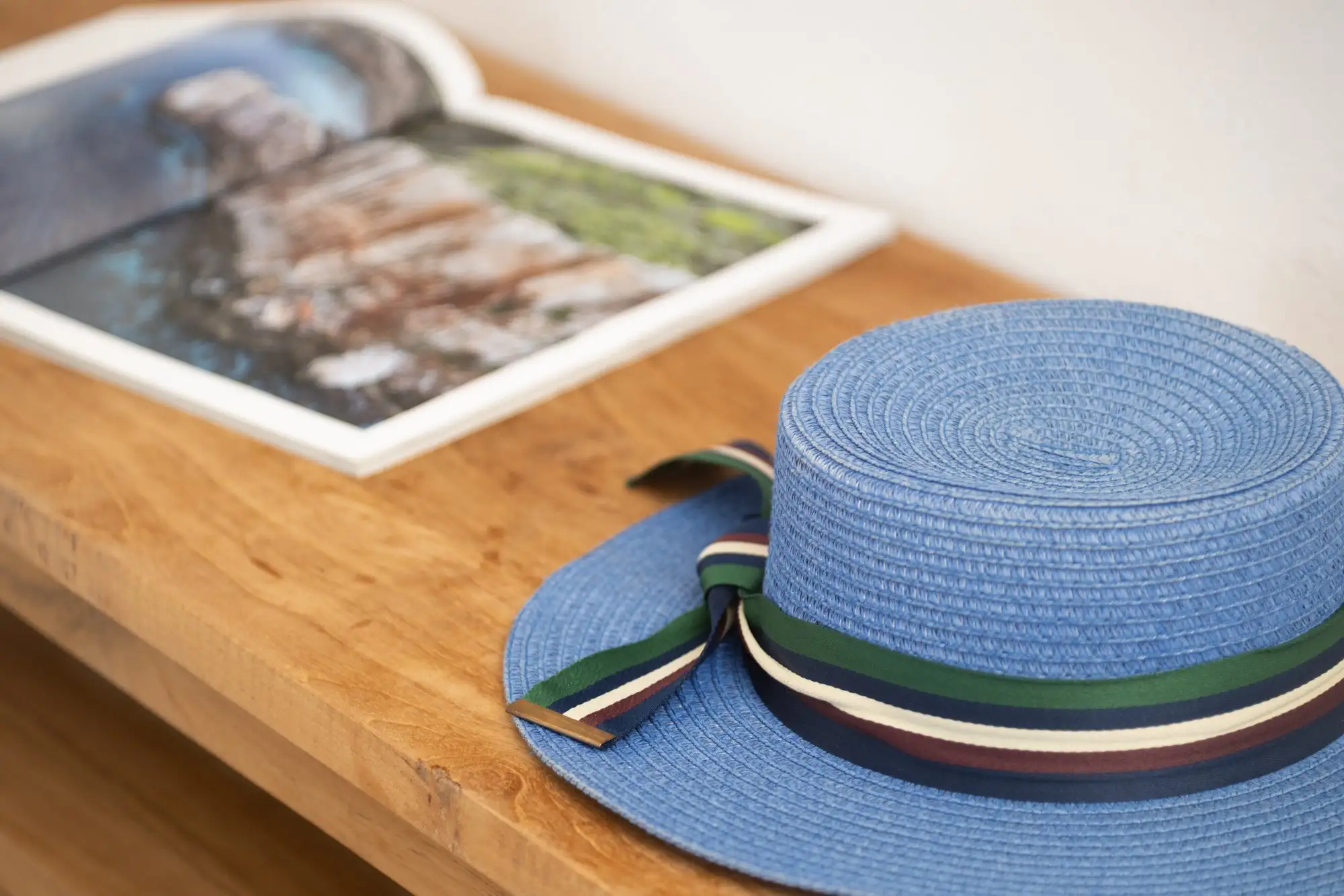 Un chapeau bleu et un livre sur une table en bois