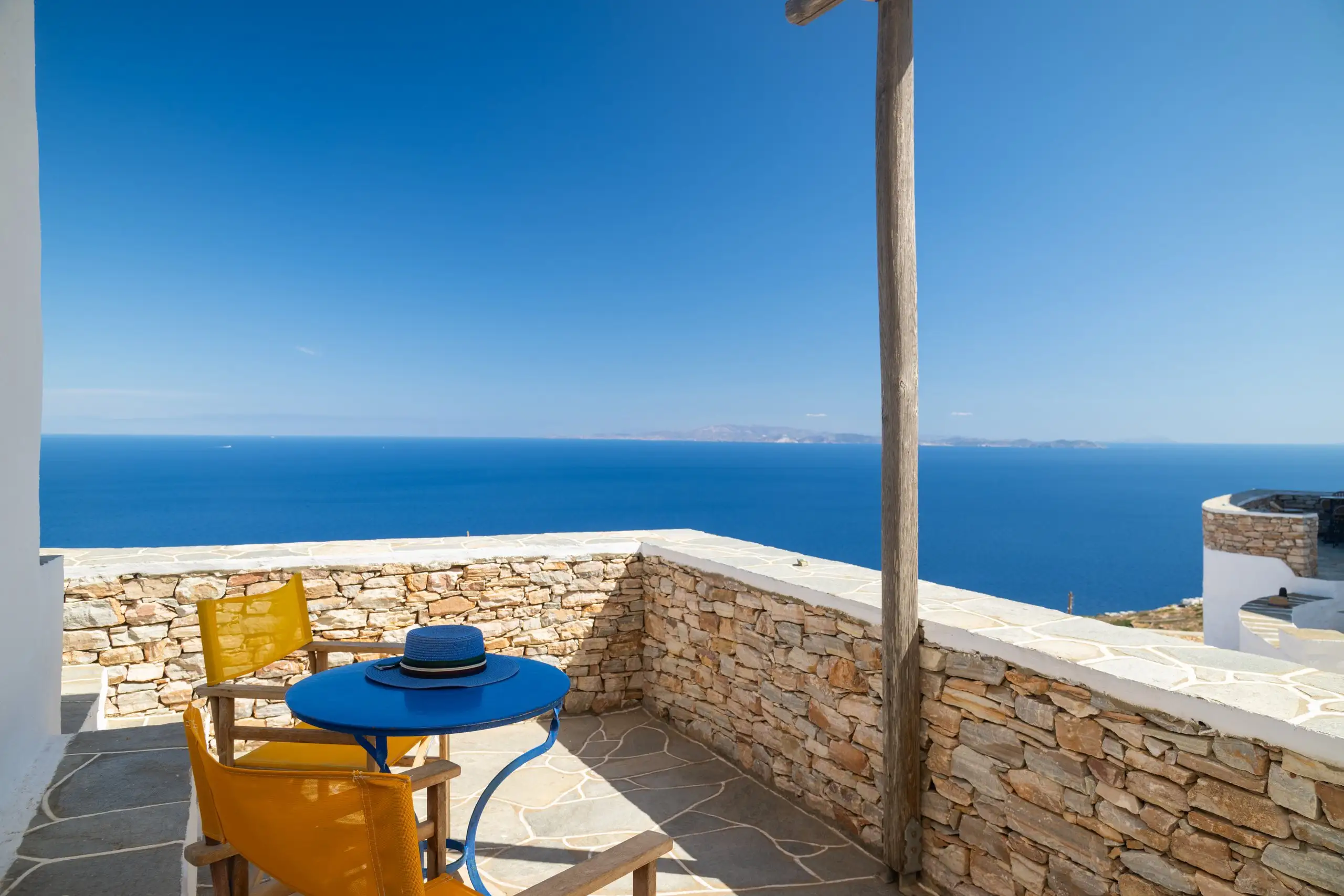 Studio Iris : terrasse avec parapet en pierre et vue dégagée sur la mer Égée