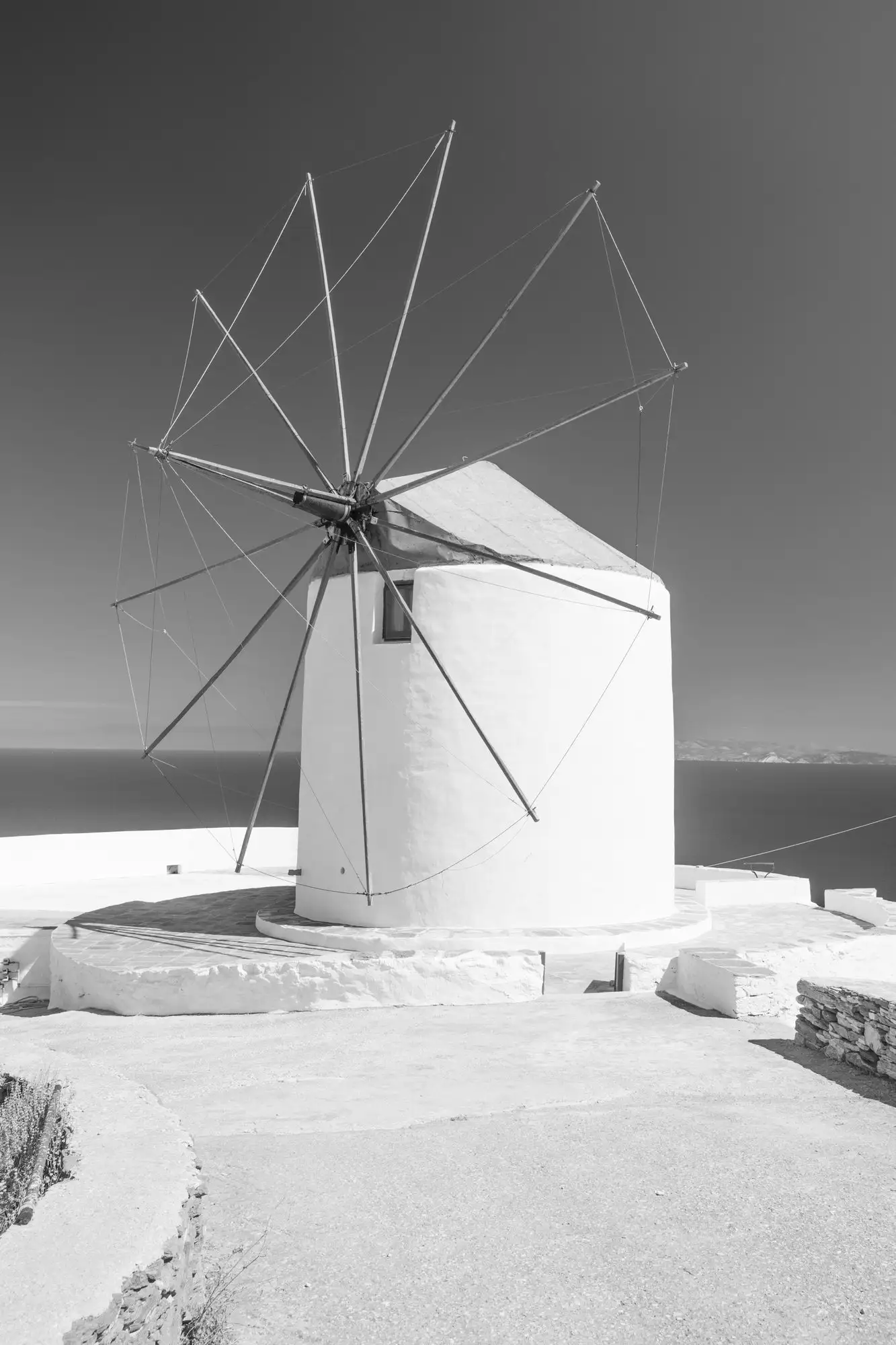 Photo en noir et blanc du moulin, avec la mer Égée au loin
