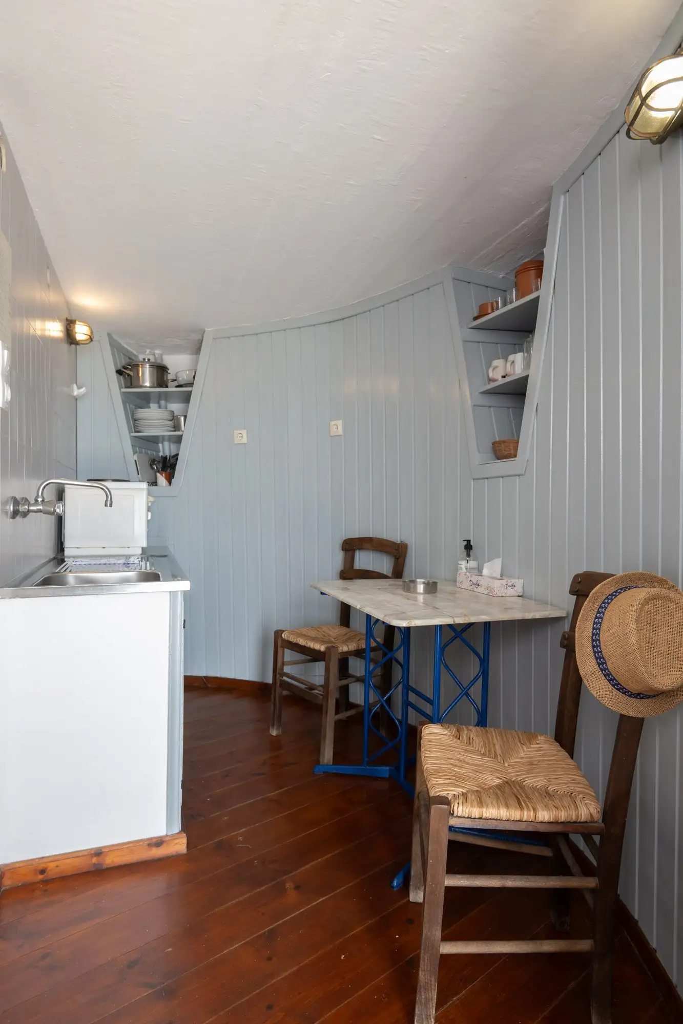 La cuisine au rez-de-chaussée du moulin, avec une petite table et des chaises paillées