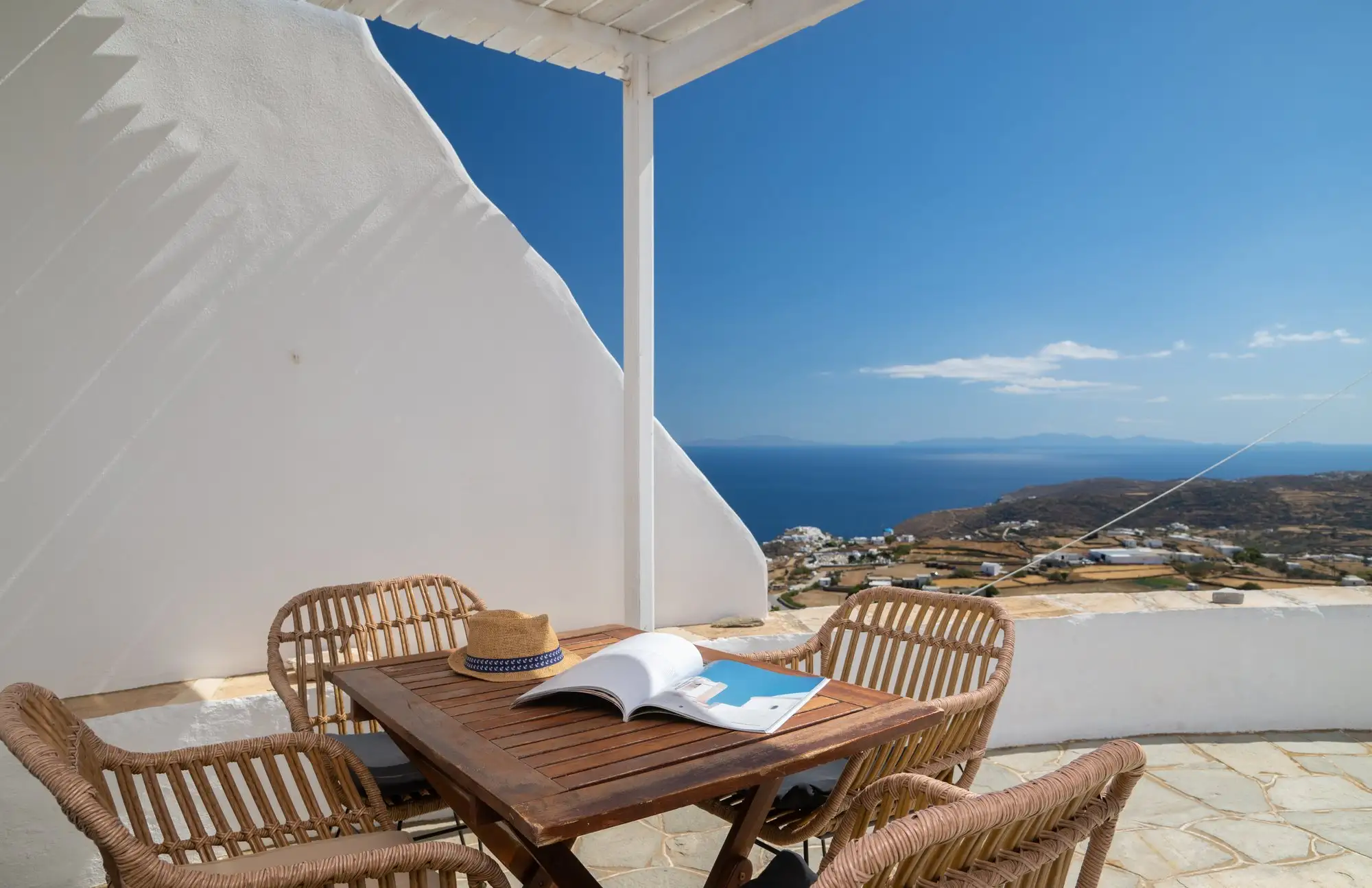 La cour du moulin, avec une table sous la pergola et vue sur la mer